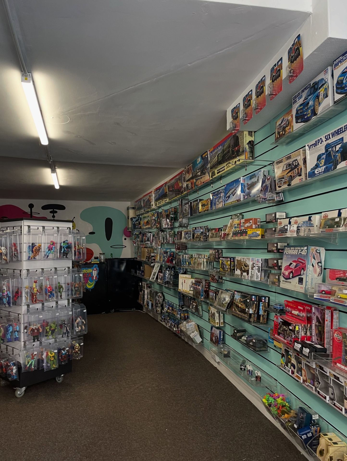 Aisle of model kits and action figures on slatwall shelving